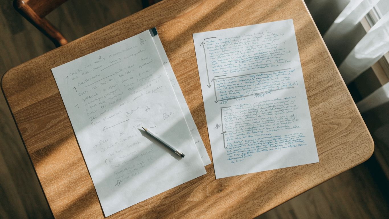 Two essay drafts beside a marked final copy