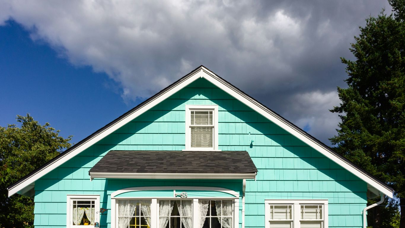 a blue house with white windows and a black roof