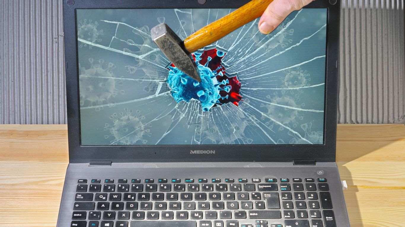 a person holding a pencil and a broken laptop