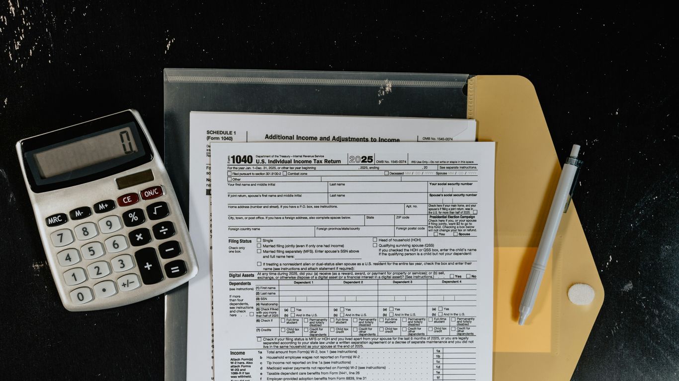 Calculator and tax forms on a dark surface.