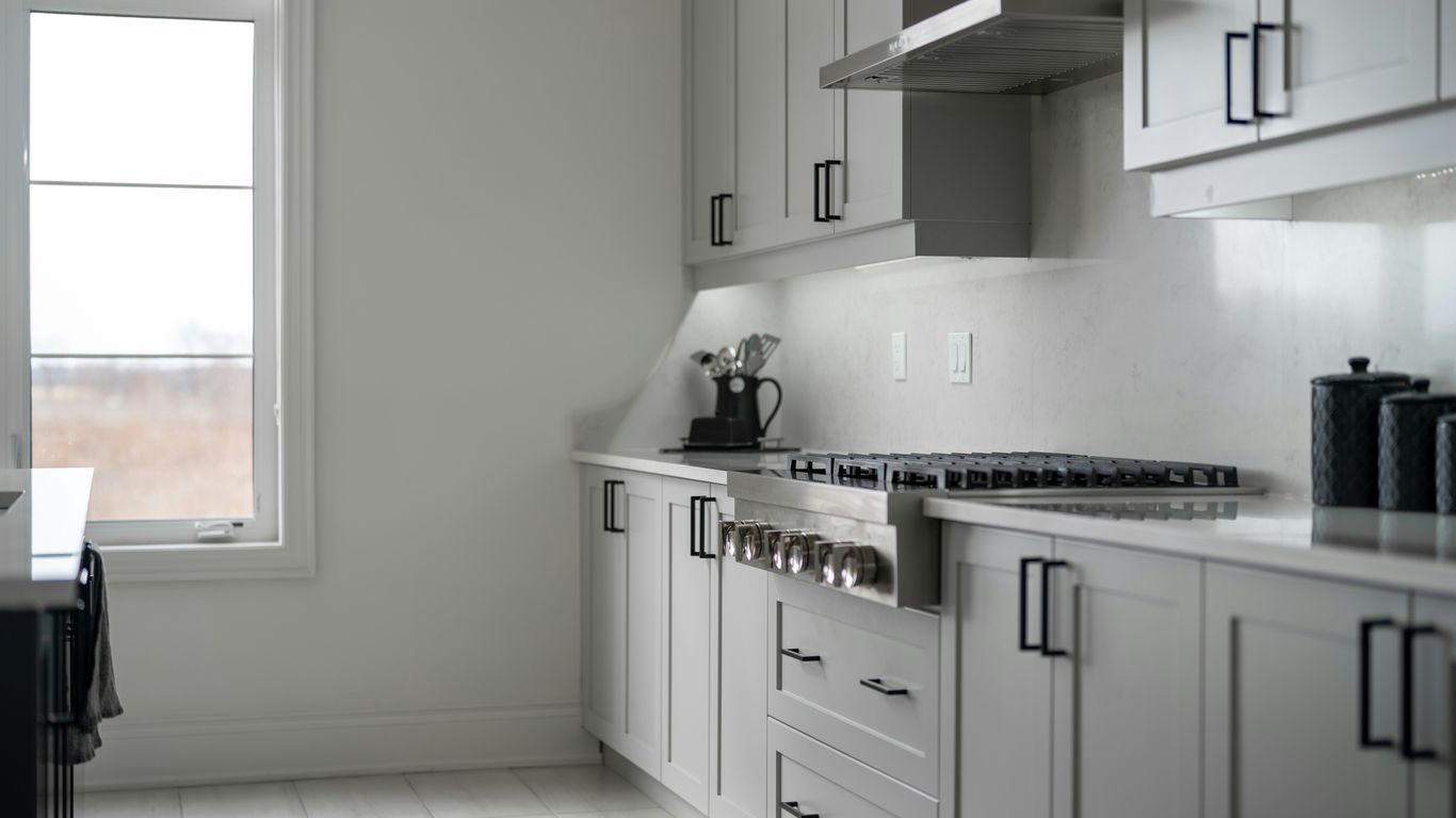 Modern white kitchen with stainless steel appliances.