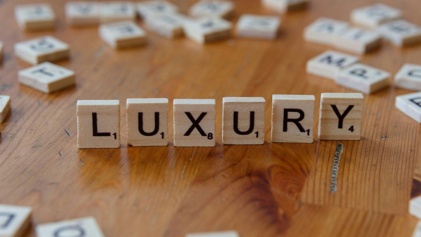 Scrabble tiles spelling the word luxury on a wooden table