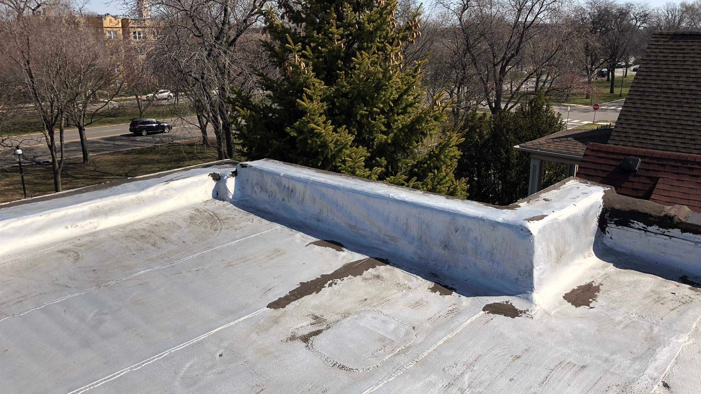 A flat roof with a white membrane and parapet walls.
