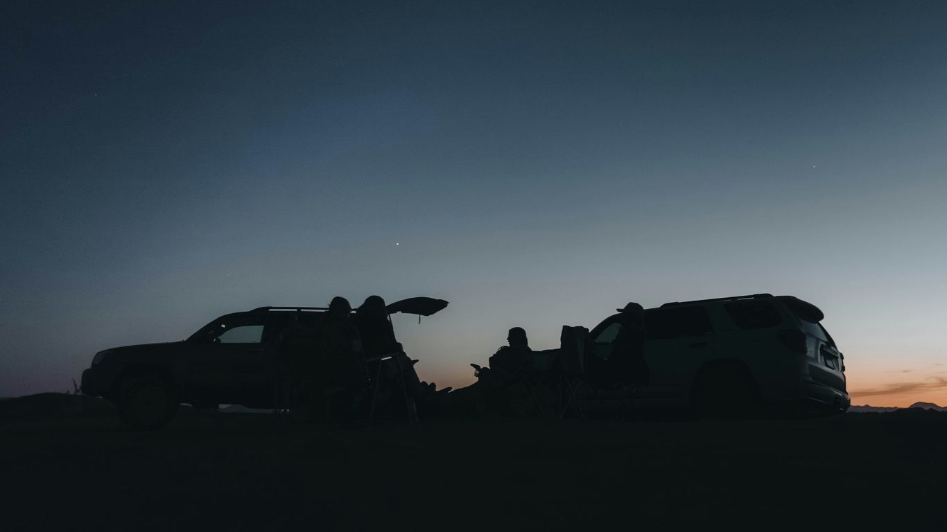 People sit around cars during dusk.