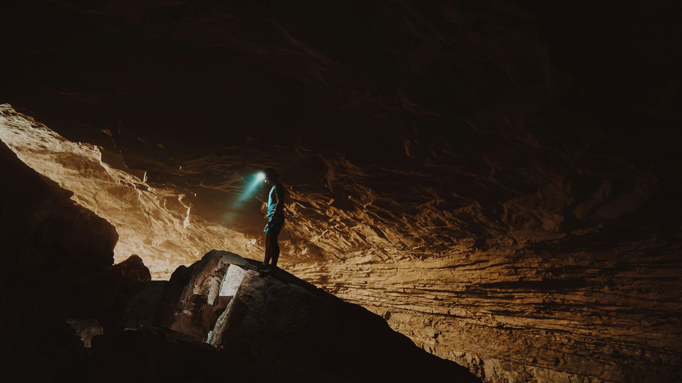 person in blue jacket standing on brown rock formation during daytime
