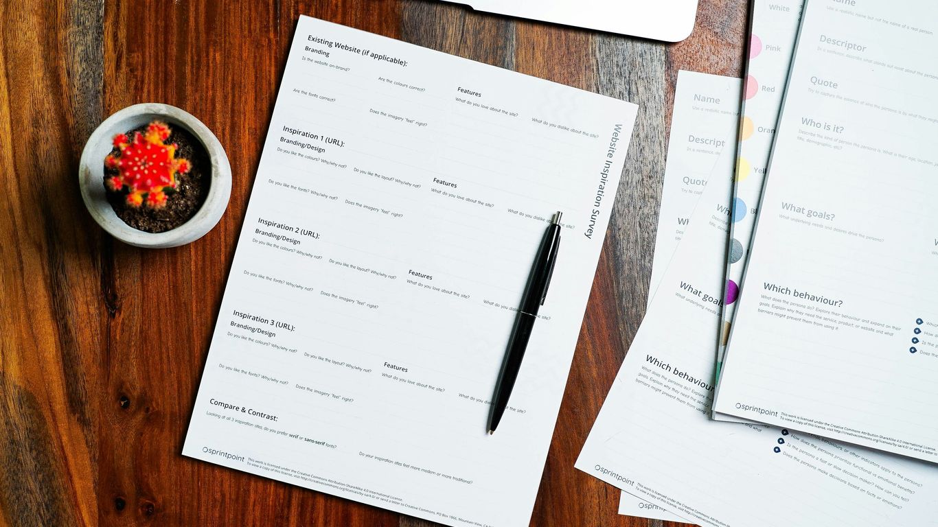 a wooden table topped with papers and a pen