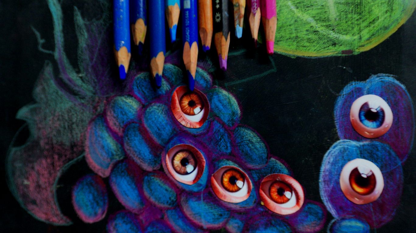 Colored pencils rest above a drawing of a creature.