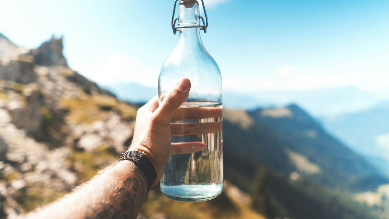 person holding empty clear glass bottle