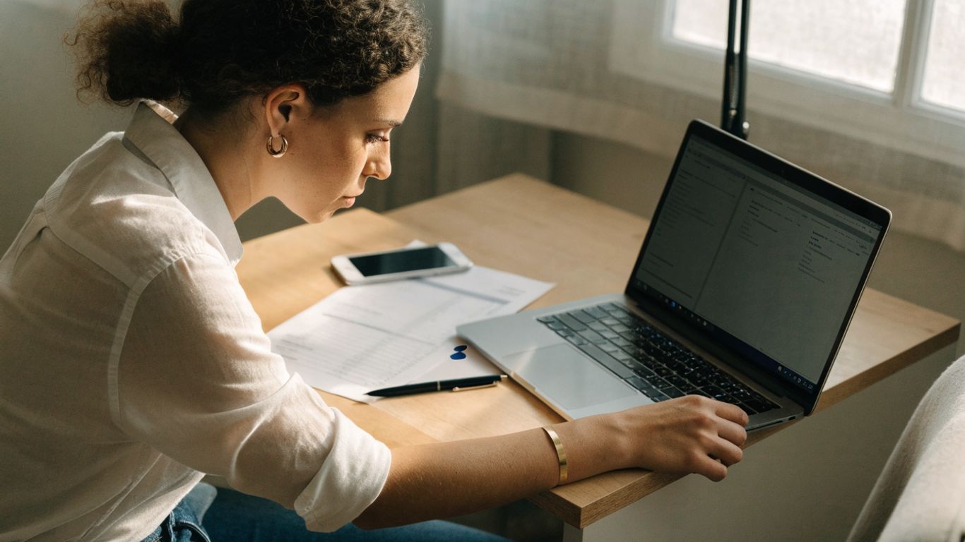 Laptop and bank statement beside notebook
