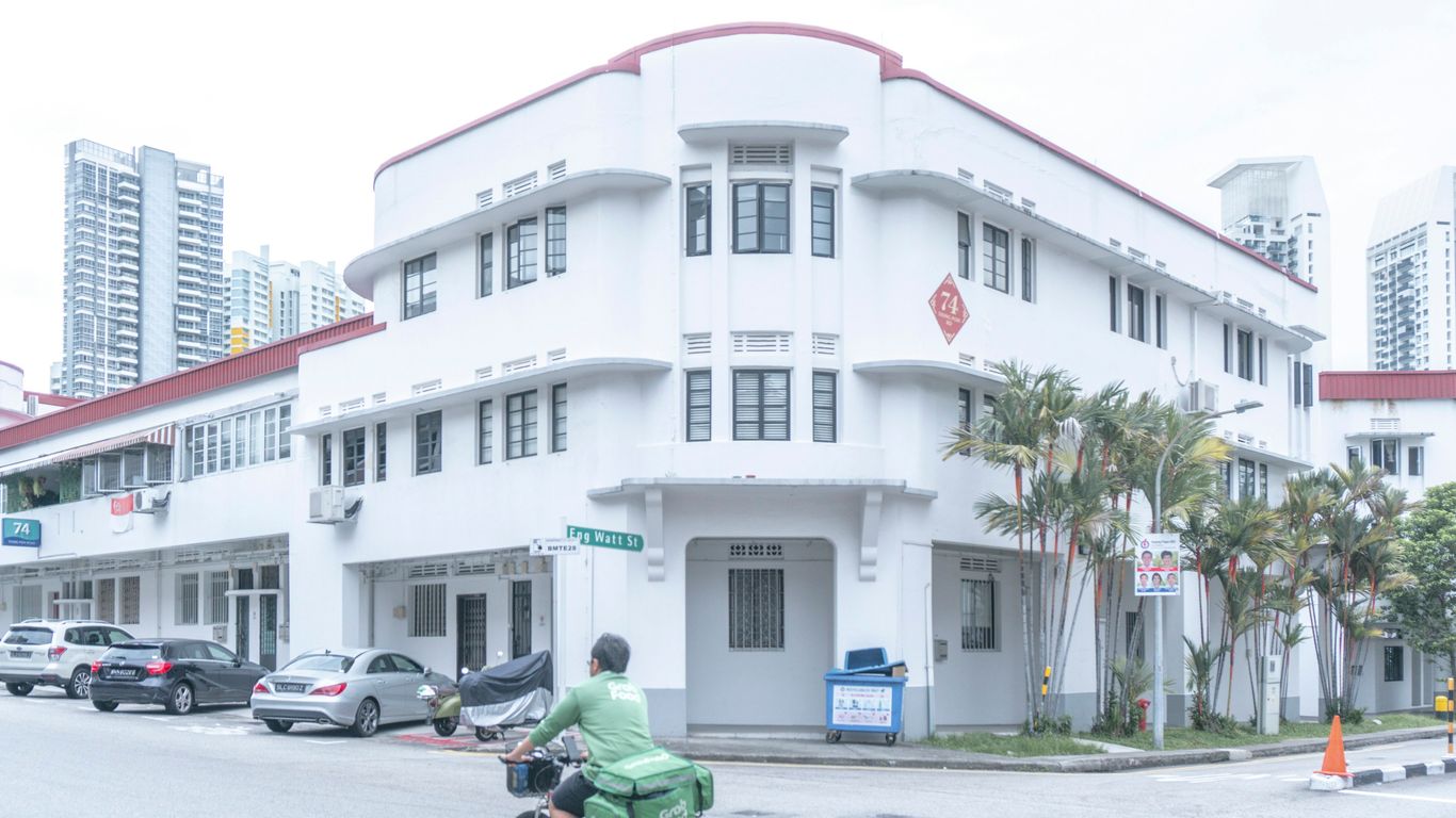 man in green shirt riding bicycle near white concrete building during daytime
