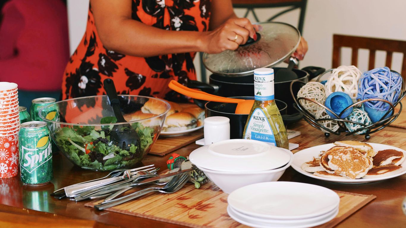 a woman in an orange dress preparing food on a wooden table