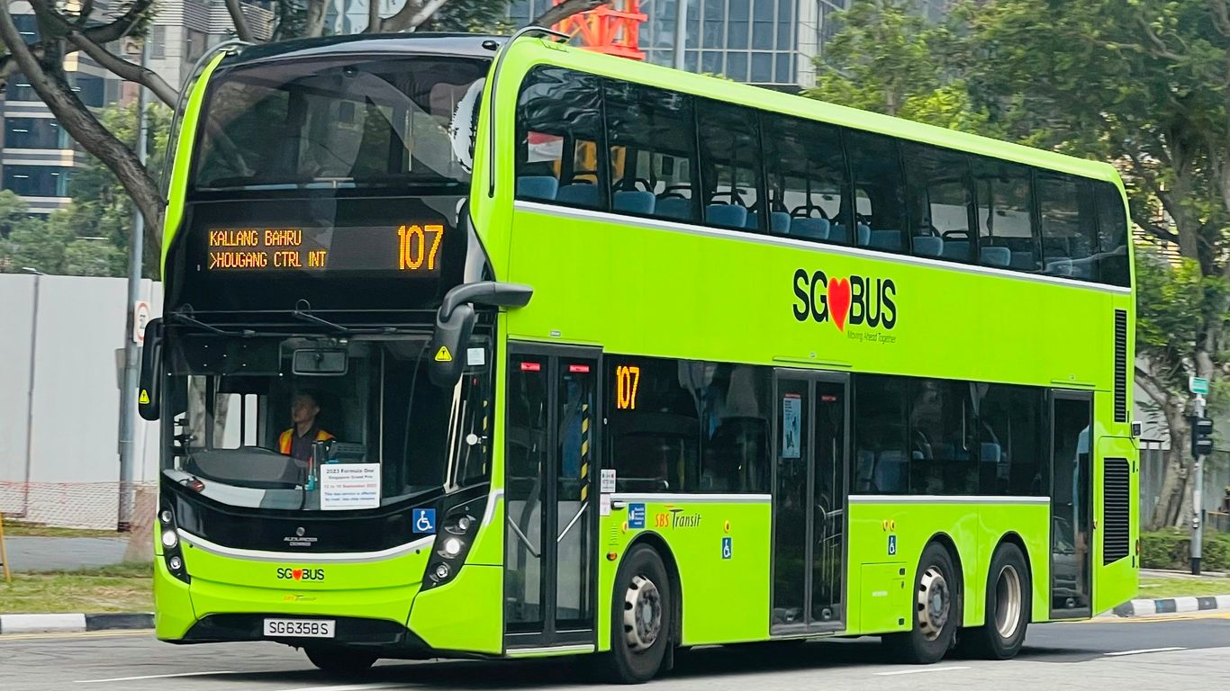 a green double decker bus driving down a street