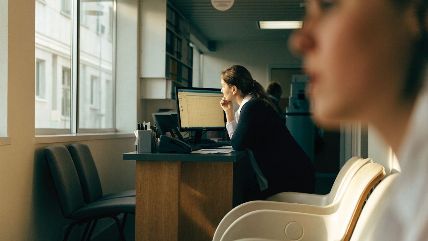 Clinic receptionist reviewing appointment calendar at a desk
