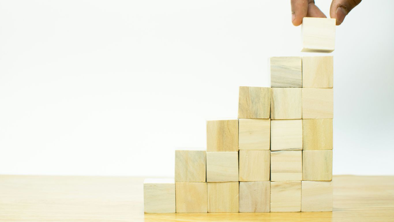 A hand is placing a block into a pyramid