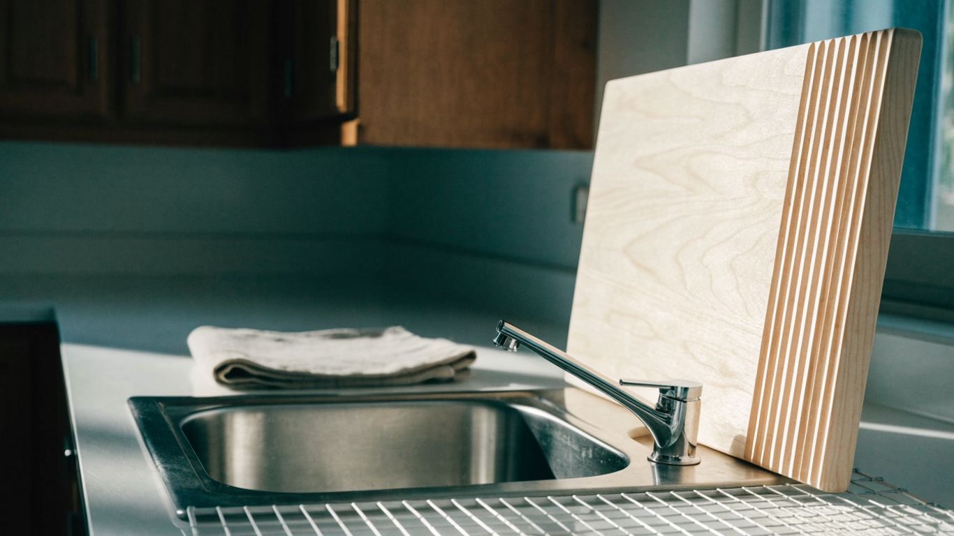 Bamboo board standing upright beside a clean kitchen sink