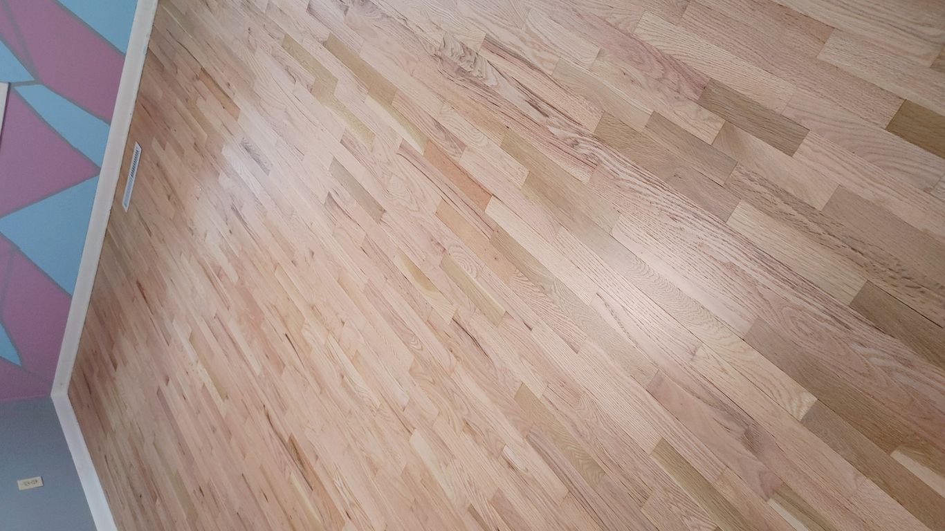 The image shows a polished wooden floor in a room.