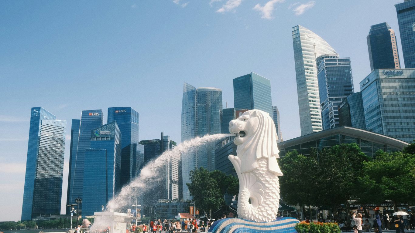 A statue of a dog spewing water in front of a city skyline