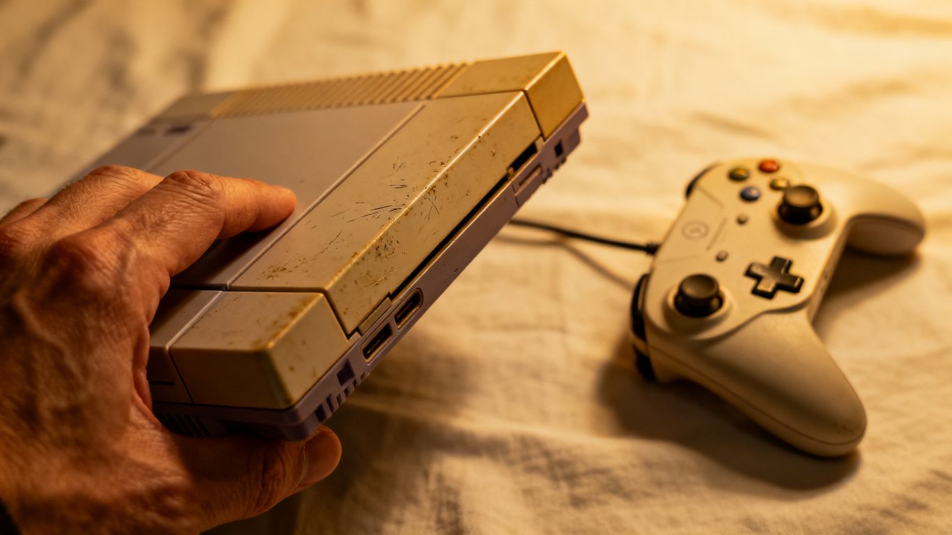 Hand holding used gaming console with controller