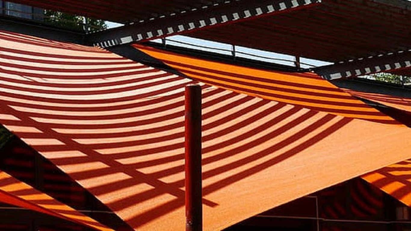 Orange awnings cast striped shadows on a sunny day.