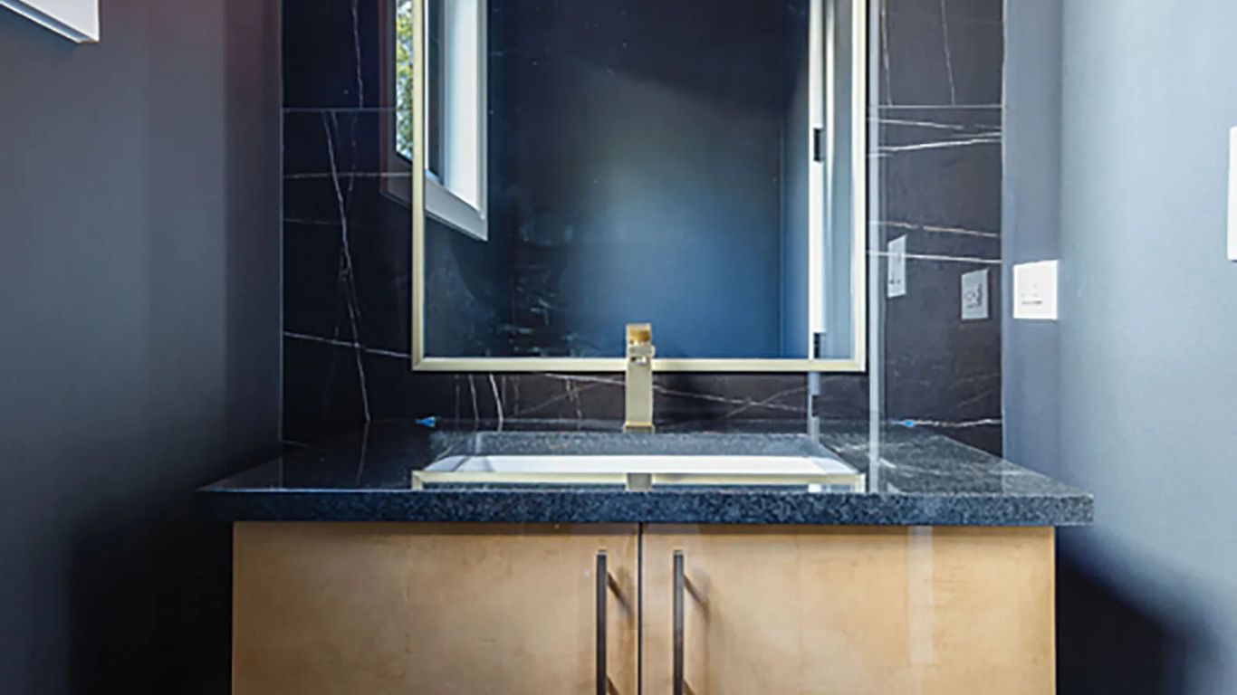 Modern bathroom vanity with gold accents and marble tile.