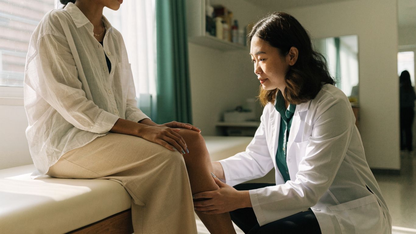 Profissional avaliando as pernas em consulta médica