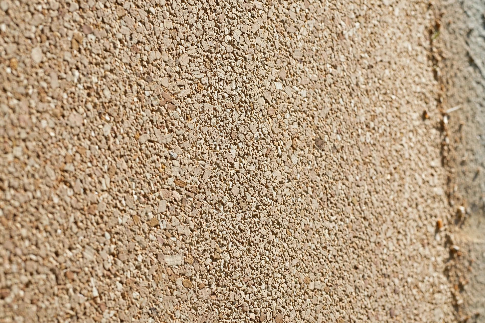 Close-up of a breathable spray cork coating showing its natural, fine textured finish on an exterior wall