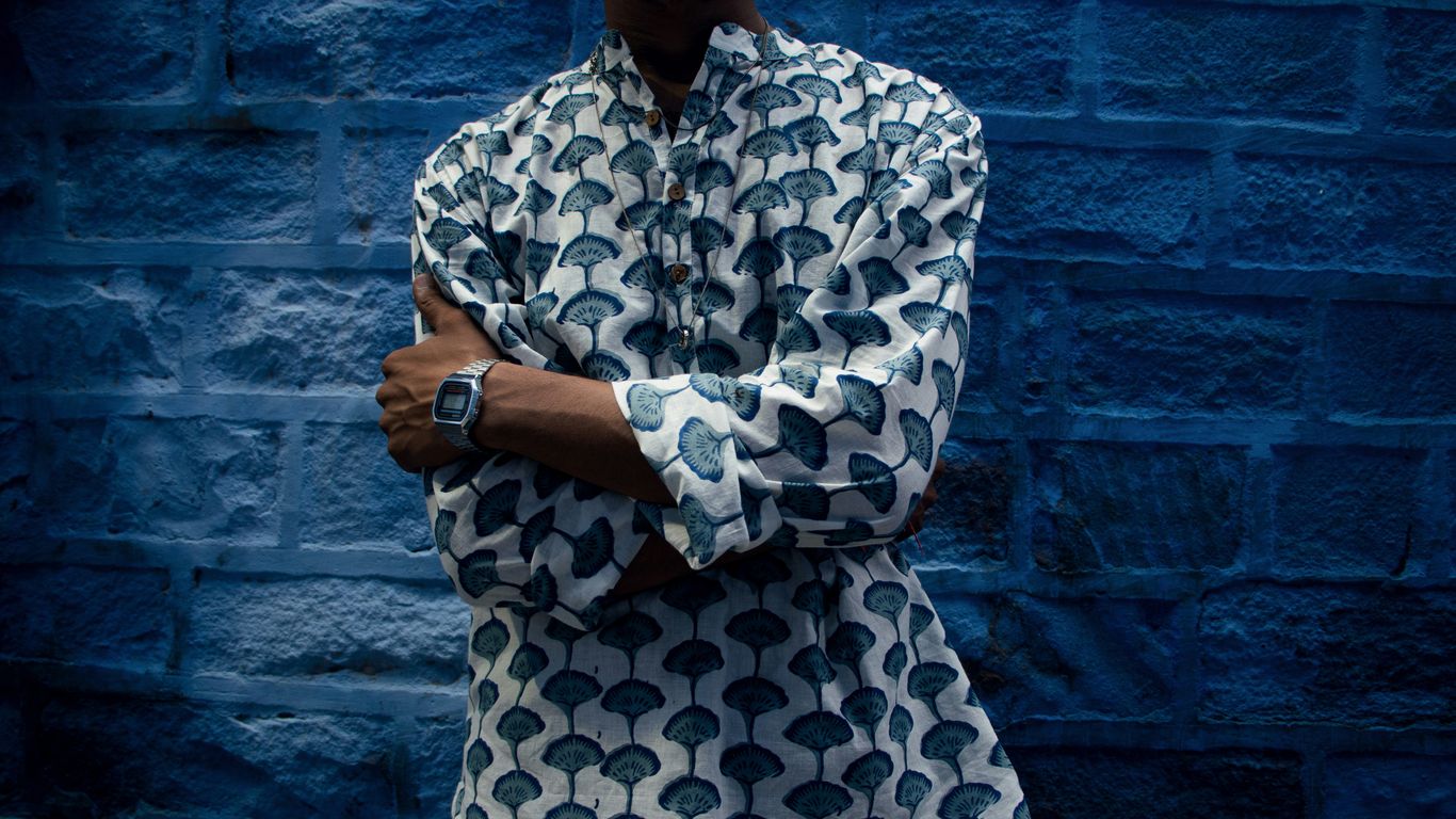 a man standing in front of a blue brick wall