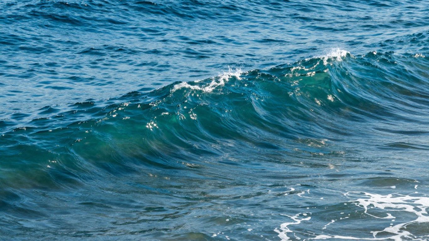 Abstract ocean waves with sunlight glinting.