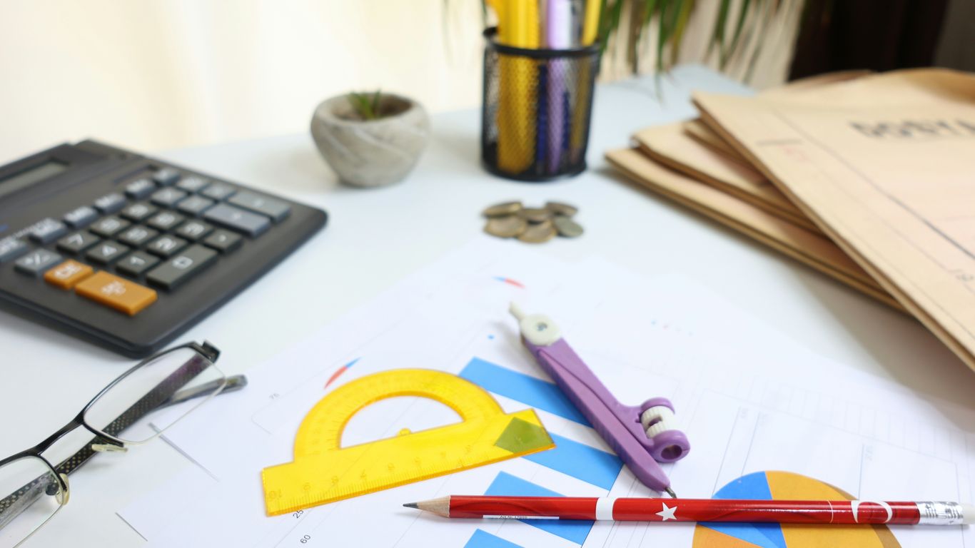 Desk with calculator, glasses, and drawing tools
