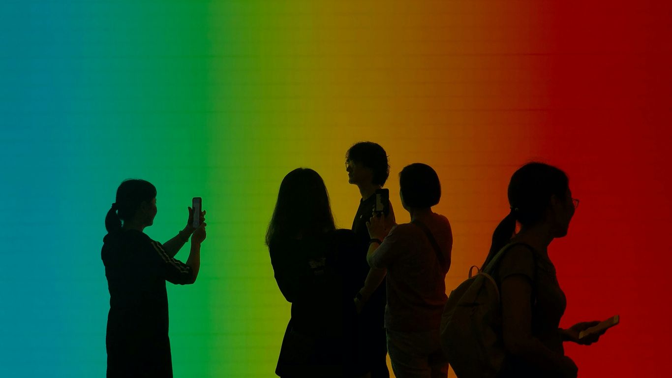 a group of people standing in front of a rainbow colored wall