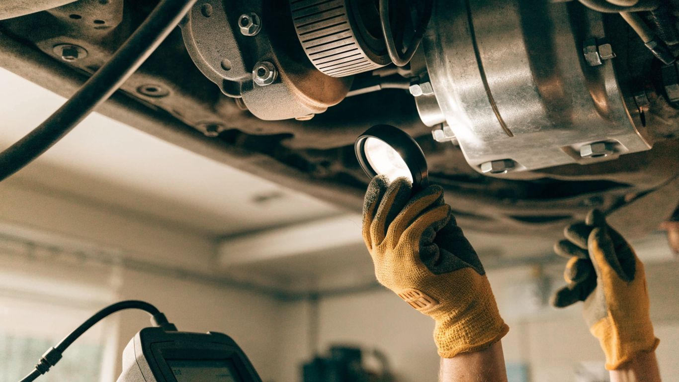 Technician inspecting a vehicle gearbox in a workshop
