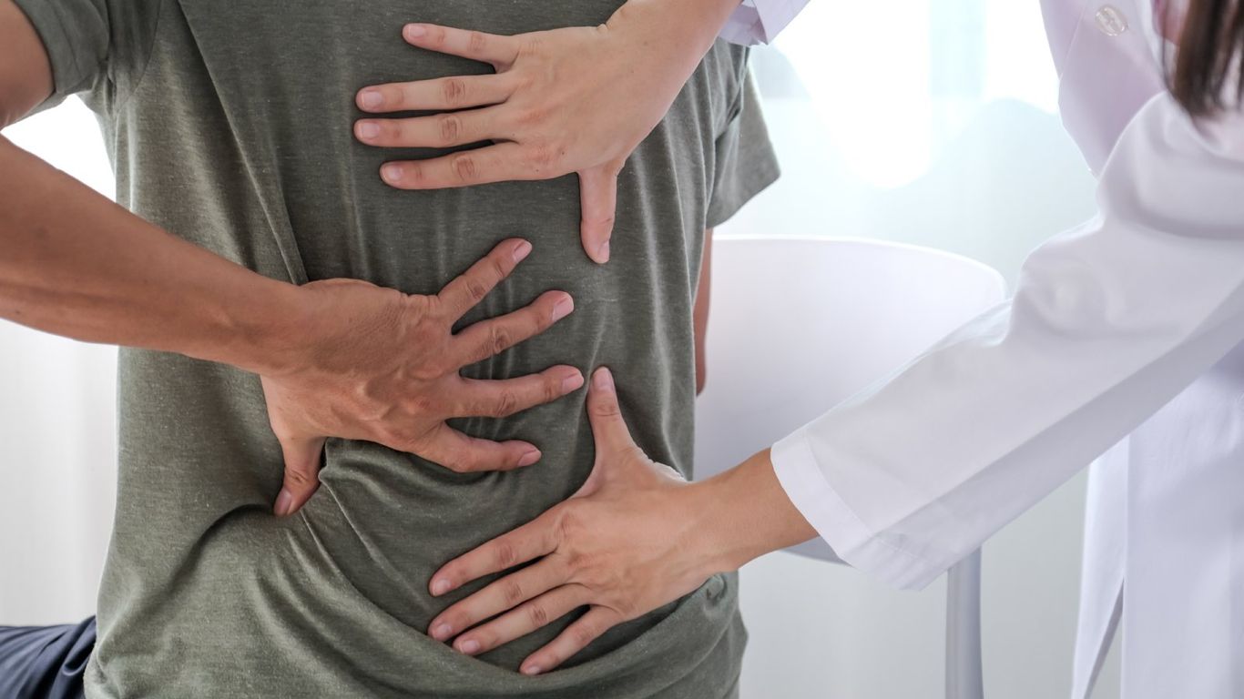 Hands examining a person's back, suggesting a medical examination.
