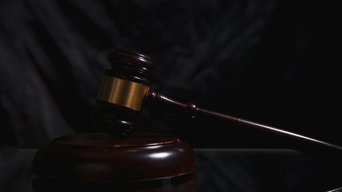 A wooden gavel rests on a dark surface.