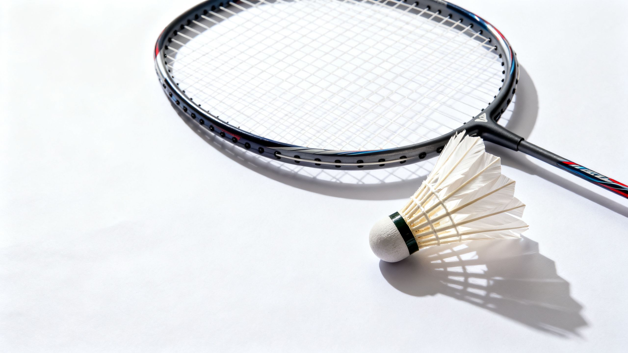 Badminton racket and shuttlecock on a clean white surface.