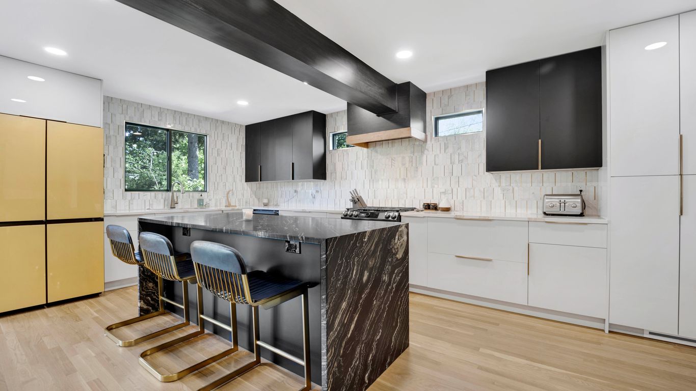Modern kitchen with a large island, dark cabinets, and gold accents.