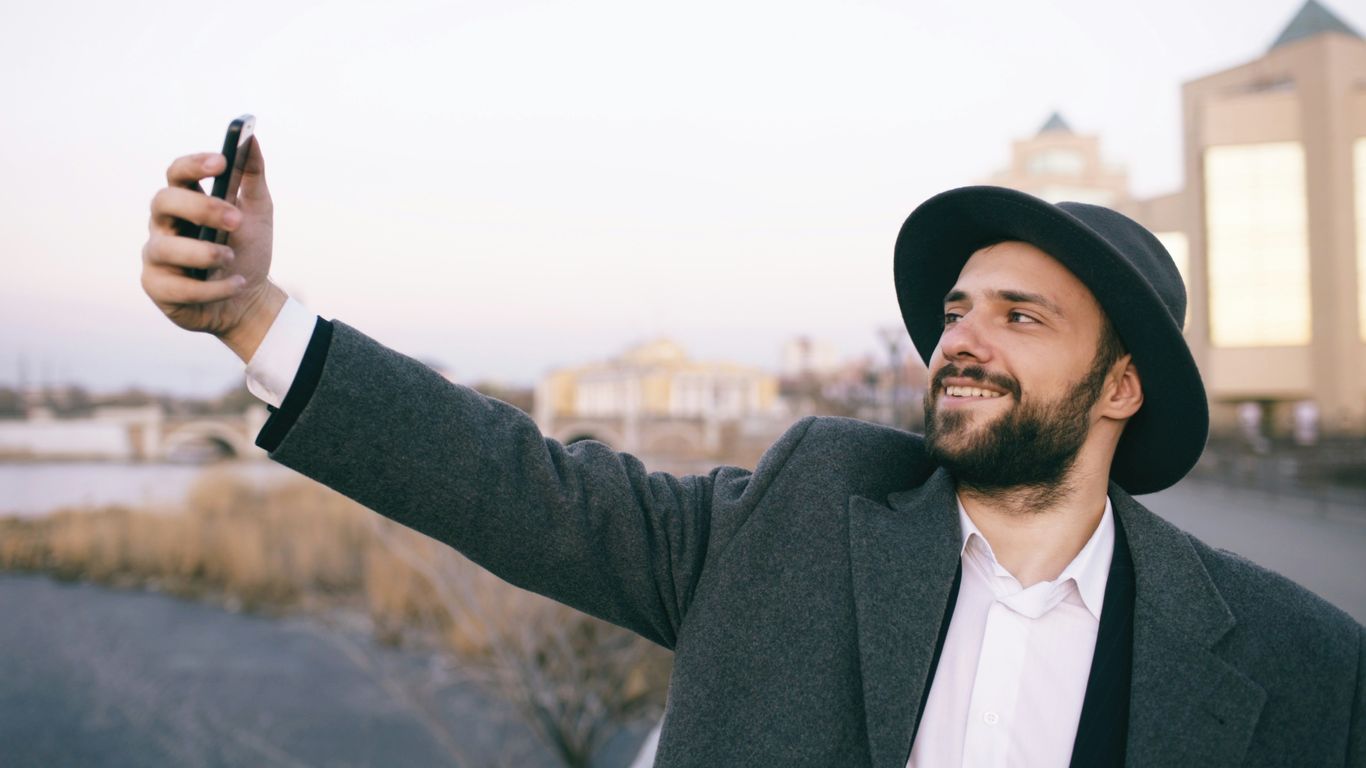 Man in hat taking a selfie outdoors