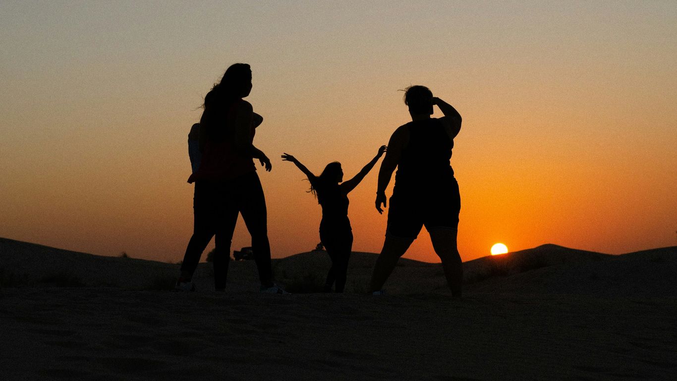 a group of people walking on a hill at sunset