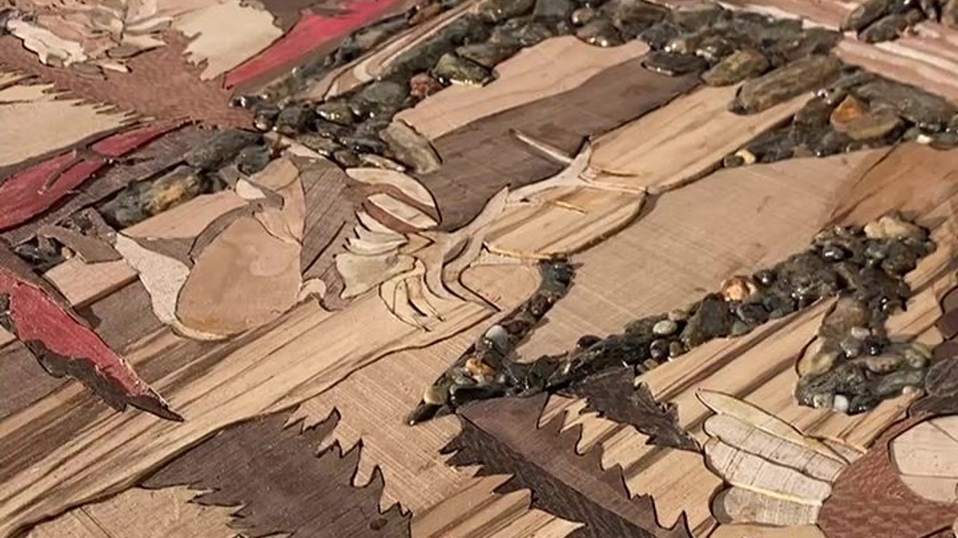 A person working on a detailed wooden art piece.