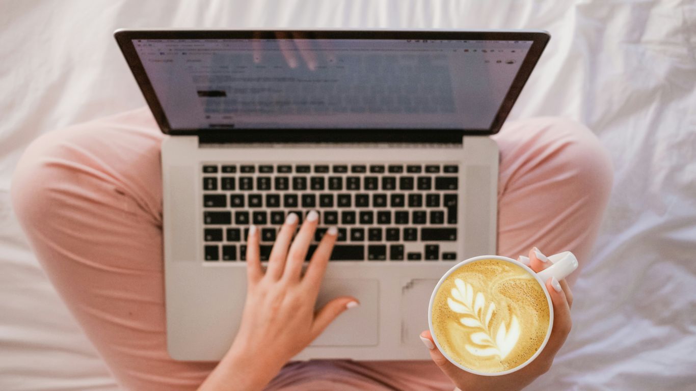 Pessoa concentrada em um computador moderno com café