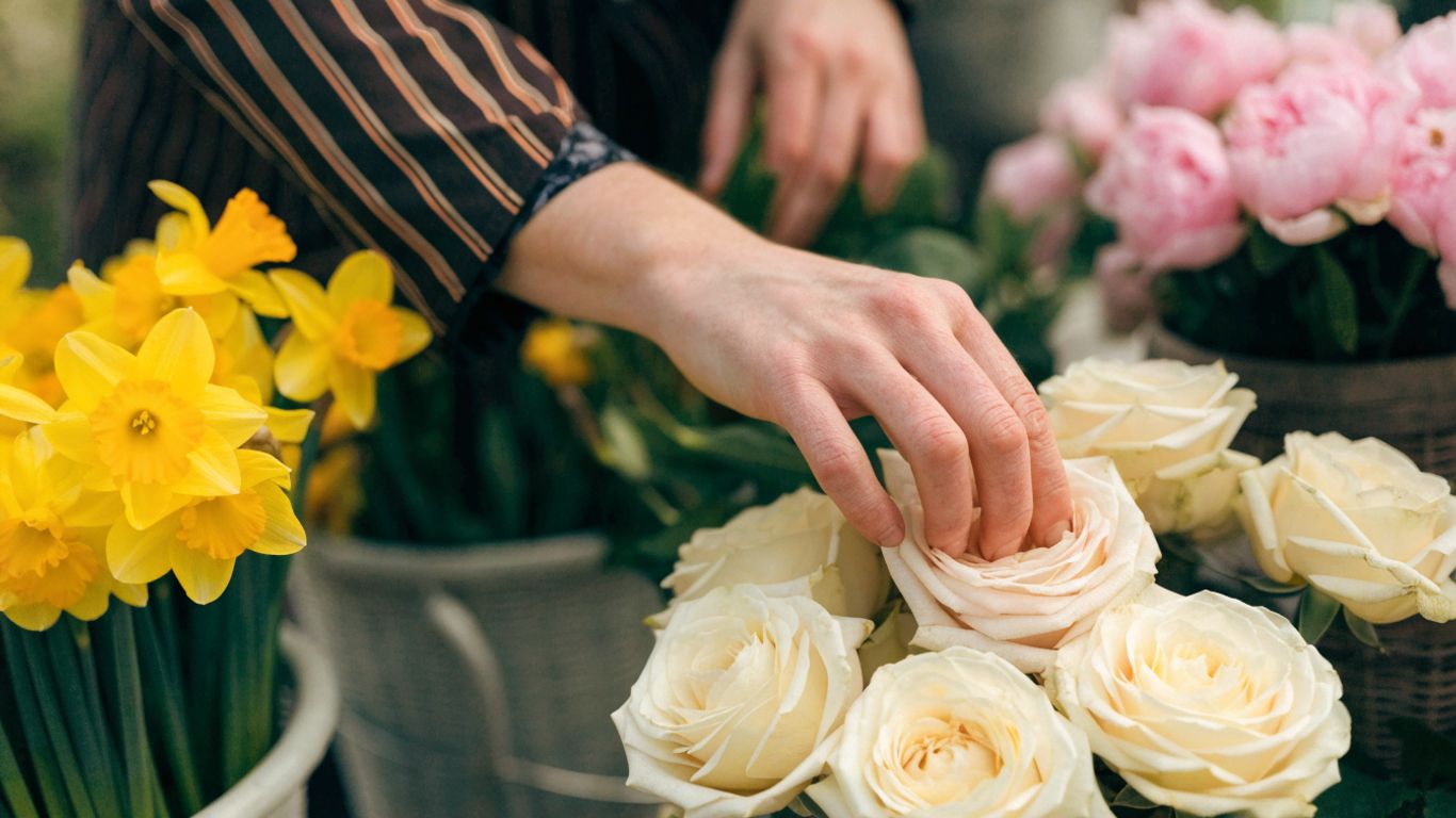 Hands choosing seasonal flowers at a neighborhood flower stand