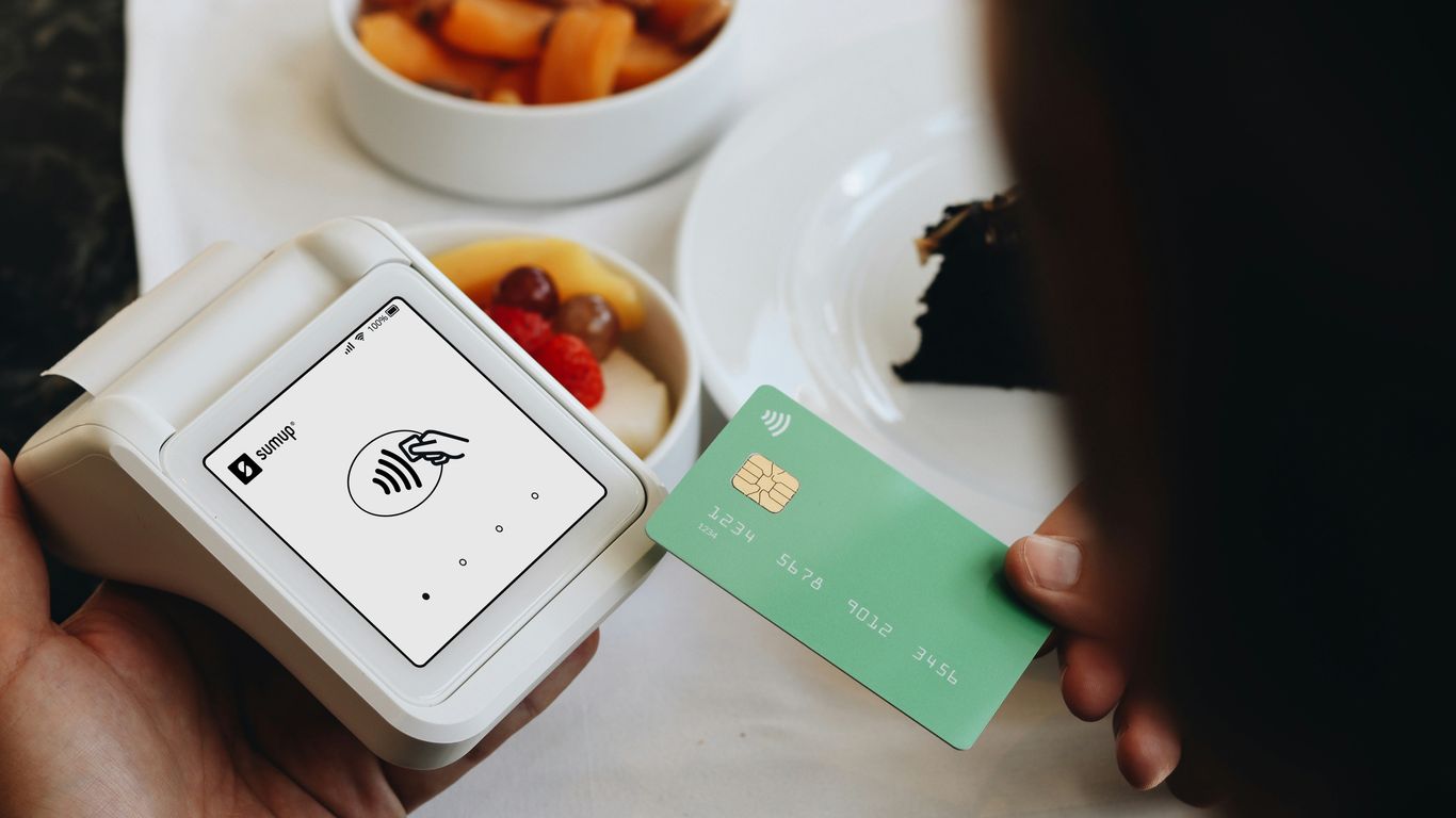 A person holding a credit card next to a bowl of food