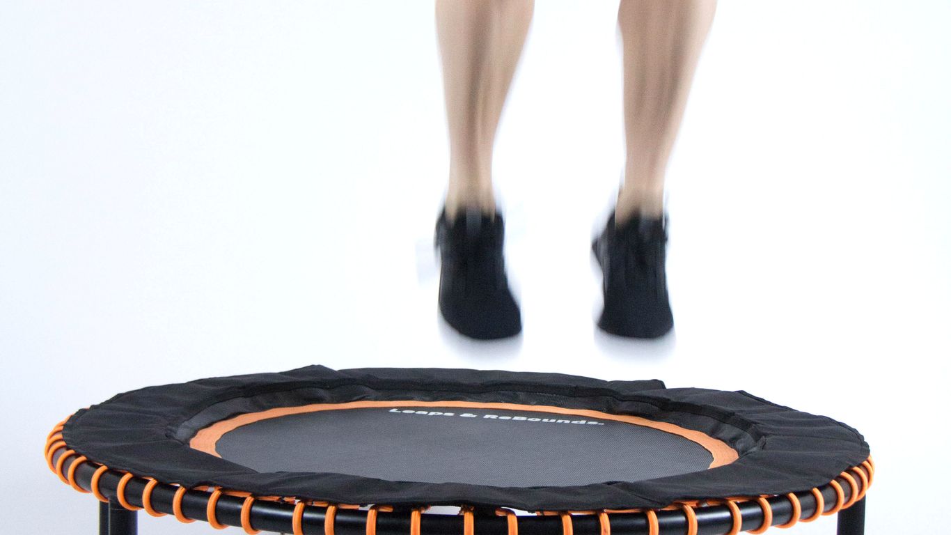 Person jumping on a small trampoline with orange accents.