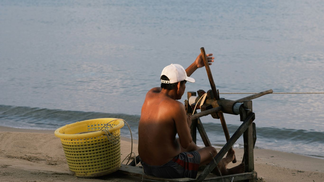 a man sitting on the beach next to a spinning wheel