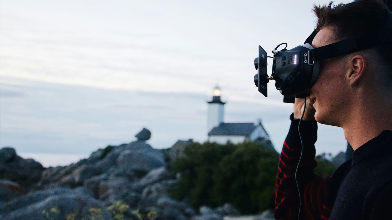 woman in red and black jacket holding black dslr camera