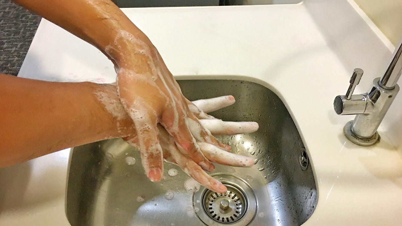 person washing hands on sink