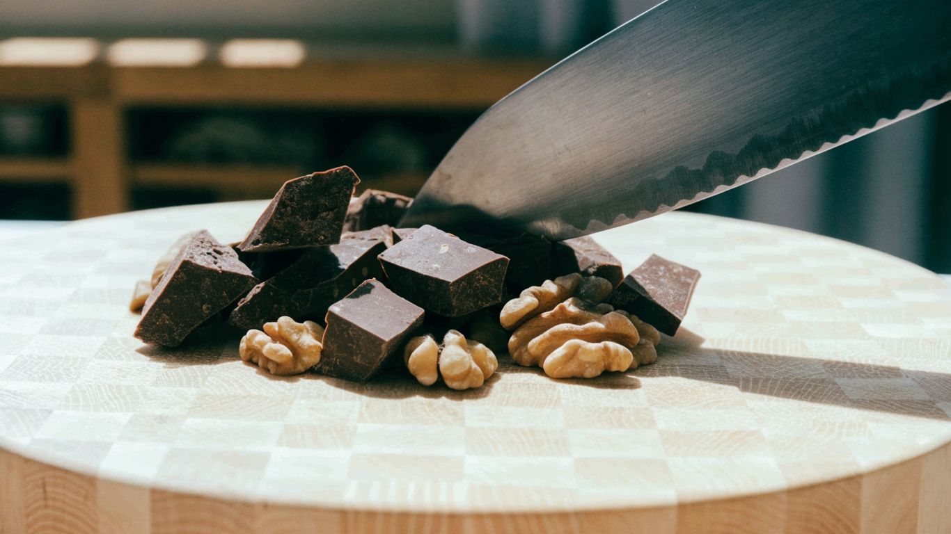 Knife chopping chocolate and nuts on maple end grain