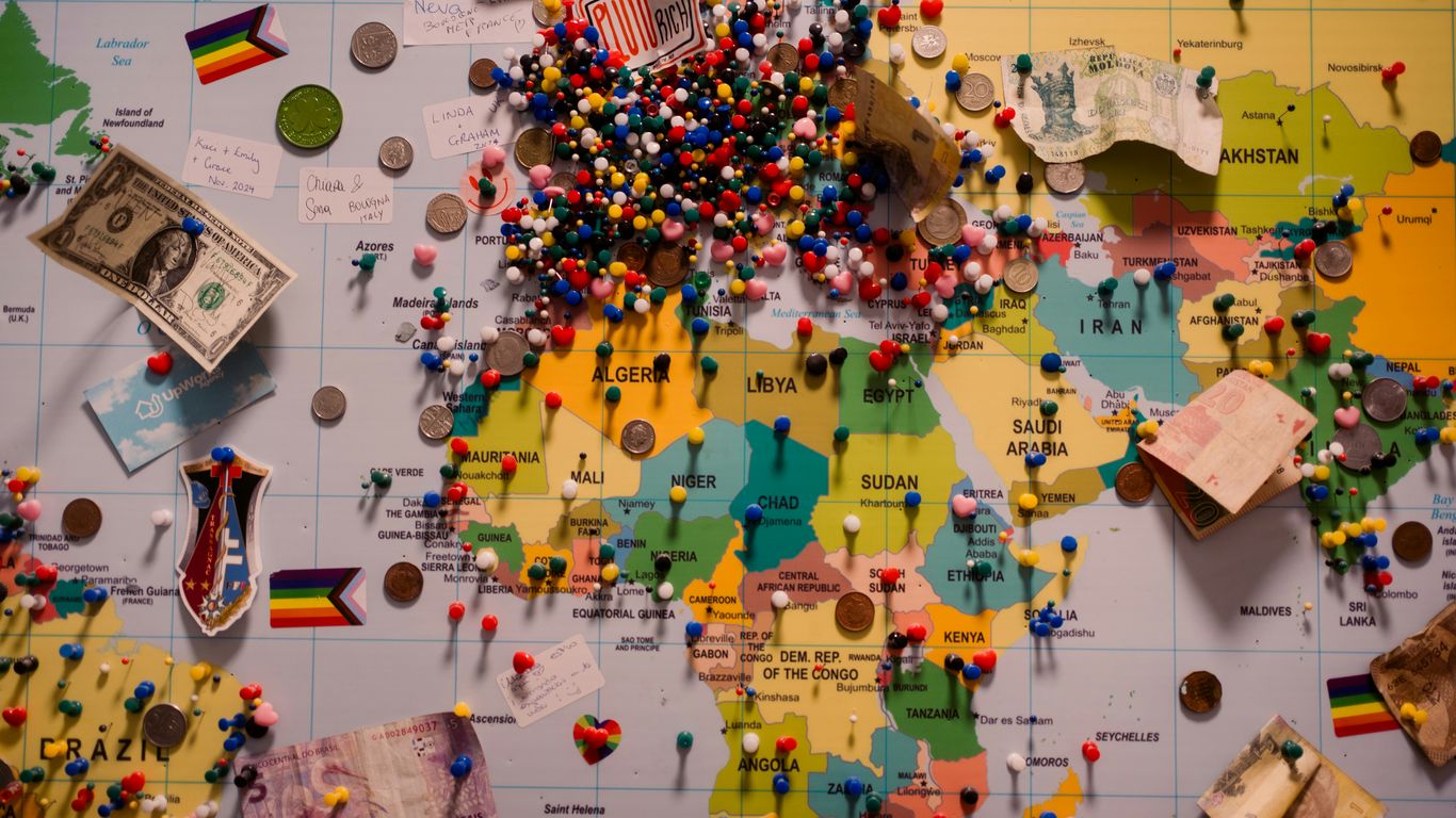 A world map is covered with pins and mementos.