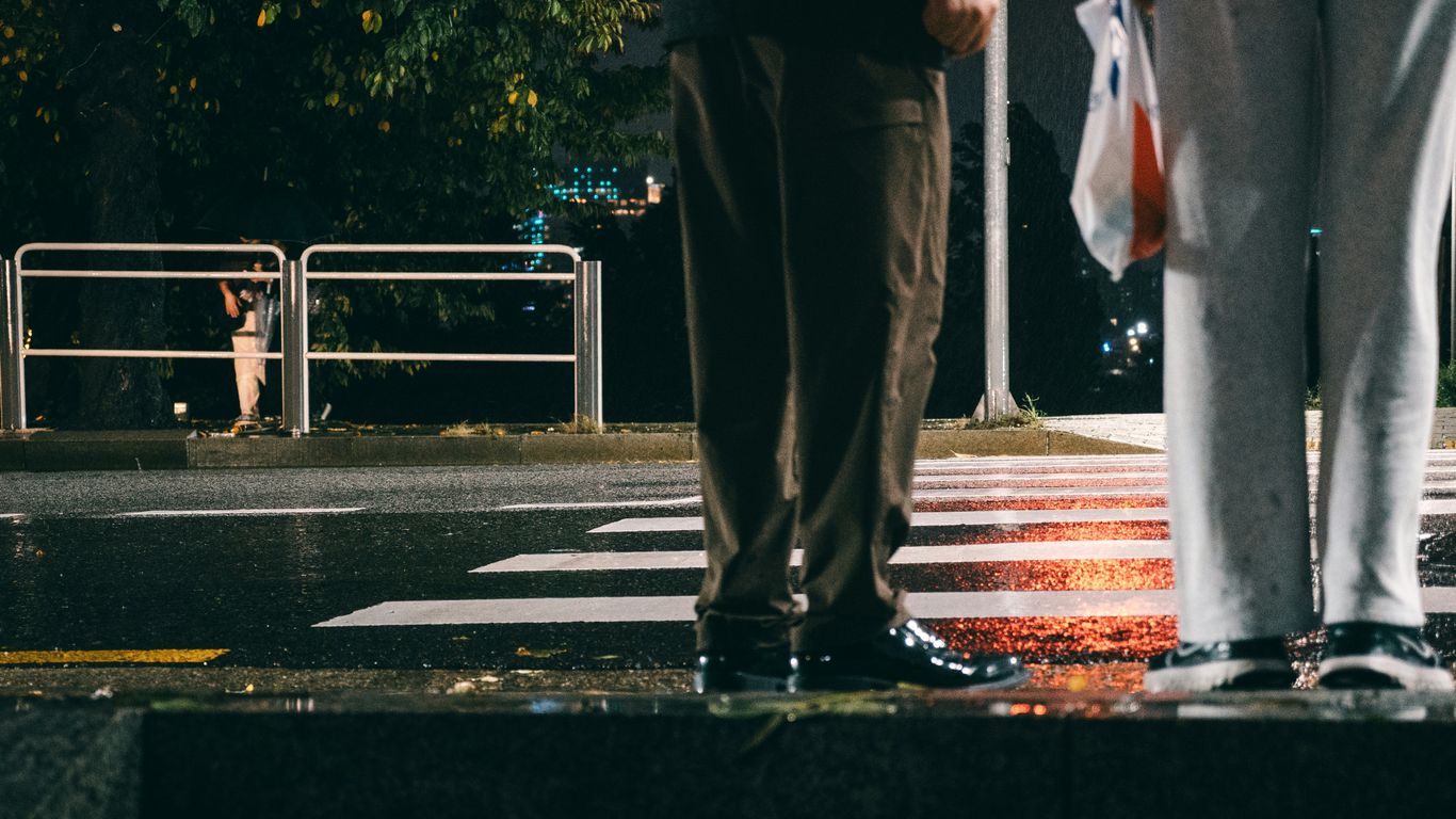Two people stand on a wet street at night.