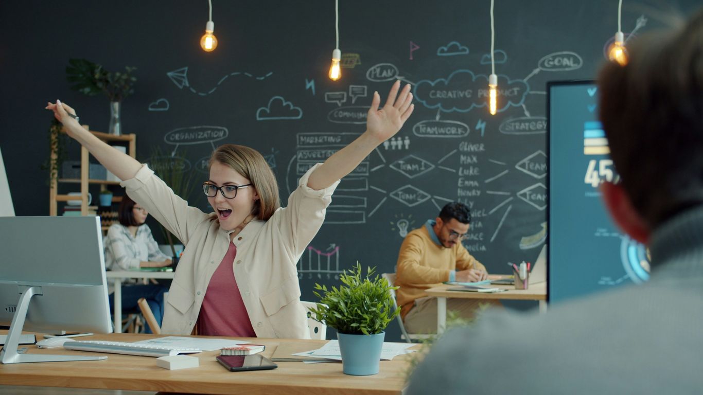 Woman celebrating success at her office desk.
