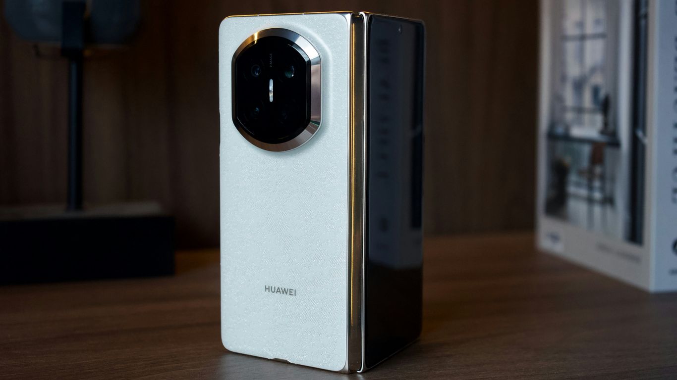 A white and gold foldable smartphone on a wooden surface.